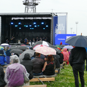Valokuva ihmisistä sateenvarjojen alla seuraamassa MILjazz-konserttia pihalla.